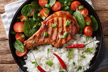 Homemade dinner of grilled pork chop with rice and fresh vegetable salad close-up. horizontal top view
