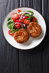 French meat balls crepinette served with fresh vegetable salad close-up. Vertical top view