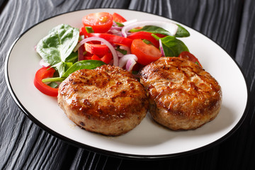 Portion of french fried meat balls crepinette and fresh vegetable salad close-up. Horizontal