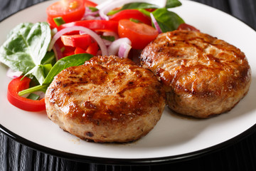 Delicious meatballs crepinette wrapped in a сaul fat and fresh vegetable salad close-up. horizontal