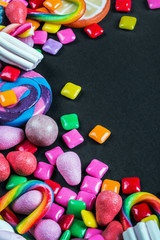 chewing gum, candy, chewing marmalade, lollipops and other sweets on black background