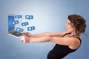 Woman holding laptop with different types of social media symbols and icons
