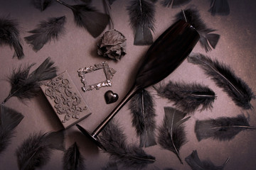 Black bird feathers, antique frame, glass heart and black rose. Gothic Valentine's Day Background....