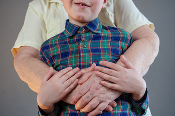 Elderly grandmother and grandson spend time together in green checkered shirt. Boy and the old woman are very attached to each other.