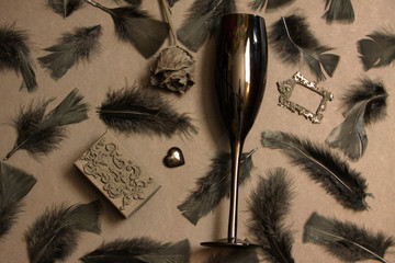 Black bird feathers, antique frame, glass heart and black rose. Gothic Valentine's Day Background....