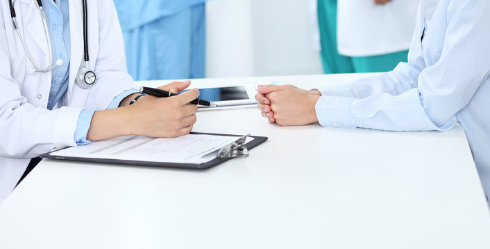 Doctor and patient discussing something, just hands at the table, white background