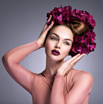 Young woman with a bouquet of purple flowers in her hair.