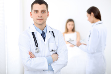 Fototapeta premium Medicine doctor standing and smiling on the background with patient in the bed