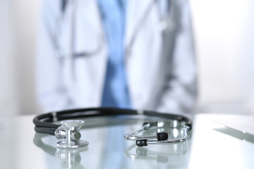 Stethoscope lying on glass desk with laptop computer at busy physician background. Medicine or pharmacy concept. Medical tools at doctor working table