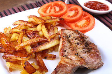 Grilled free-range beef steak with potato free, fresh tomatoes and sauce on a brown stone background