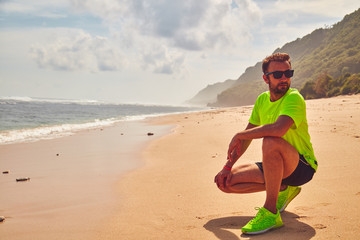 Sportsman stretching on a exotic tropical beach after jogging / exercising.