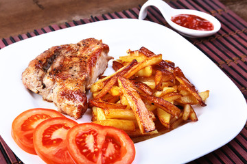 Grilled free-range beef steak with potato free, fresh tomatoes and sauce on a brown stone background