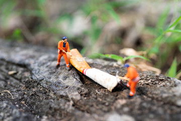 Miniature people: Worker are destroying cigarettes which is air pollution not safe for people. Use image for health concept.