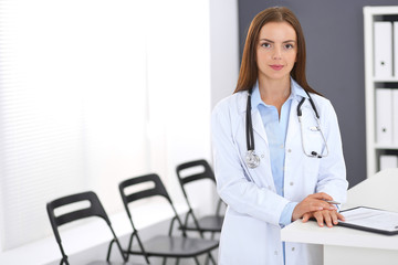 Doctor woman at work. Portrait of female physician standing near reception desk at clinic or emergency hospital. Medicine and healthcare concept