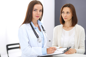 Doctor and  patient  discussing something while standing near reception desk in emergency hospital. Physician at work in clinic. Medicine and health care concept