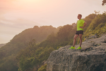 Fototapeta premium Sportowiec robi przerwę po treningu na tropikalnym klifie.