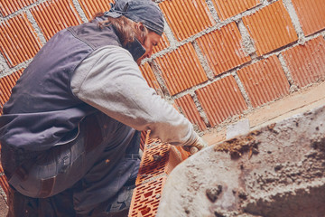 Real construction worker bricklaying the wall indoors.