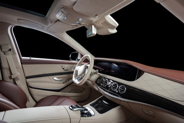 Car interior luxury. Beige comfortable seats, steering wheel, dashboard, climate control, speedometer, display, wood decoration, isolated on black, clipping path included