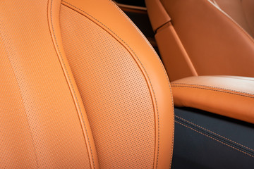Part of red leather car seat with the unfocused car interior on the background