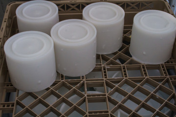 cheese molds ready to clean with soap in the dishwasher on a brown plastic tray 