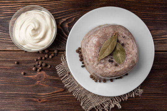 Jellied aspic with chicken meat, traditional Russian dish holodets on dark wooden background.