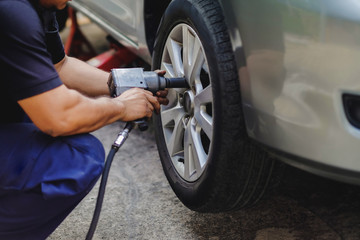 Tire Replacement concept. Mechanic Using Electric Screwdriver Wrench for Wheel Nuts in Garage. Car Maintenance and services © blacksalmon