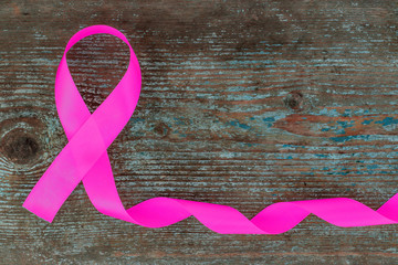pink silk - breast cancer awareness symbol on the wooden background with copy space