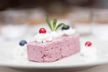 Close up on a delicious slice of cream and berry cake served on a white dish and resting on a...