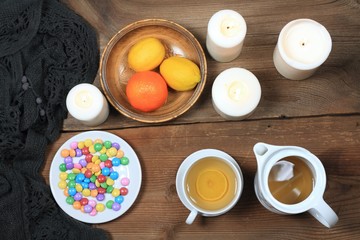 Hygge autumn or winter time for tea. Flat lay with chocolate candies called lentils, candles, lemon and tangerin