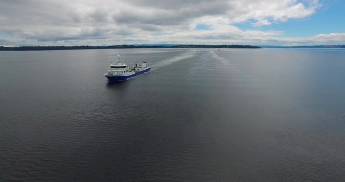 Aerial view with drone of a wellboat sailing through the archipelago of Chilo&eacute;
