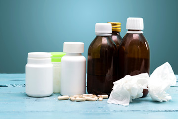 Dirty paper handkerchief and syrup bottles and drug on blue wood table, influenza concept