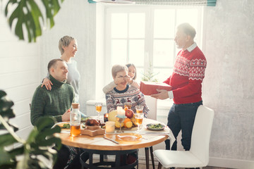 Family celebration. little girl is closing her mother's eyes while grandparent is holding a big red box with a present. surprise fpo mummy
