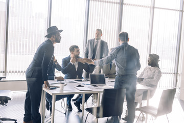 Serious Indian CEO in interacting with multiracial vendors at corporate meeting, explaining development project strategy, proving them to continue cooperation.