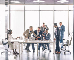 Hot debates. Group of interracial business partners disagree with company CEO, dressed as Arab, people have dispute, using lots of hand gestures, but staying positive at meeting in office.