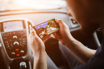 Men are playing on the phone. On the background of the car.Warm light.