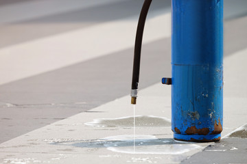 Blue fire extinguisher after used on the ground with chemical liquid dropping from the pipe