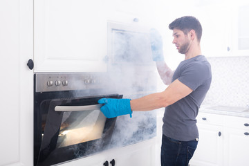 Man Opening Oven Filled With Smoke