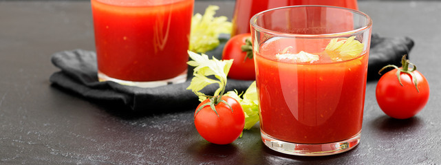 Tomato juice in glass with celery, cherry tomato  on dark background.