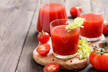Tomato juice in glass with celery, cherry tomato  on dark background.