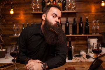 Handsome young bartender playing with his beard. Great personality .
