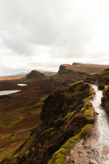 Hiking path at Quiraing on a moody cloudy autumn day with orange vegetation and panorama view of Skye (Isle of Skye, Scotland, Europe)