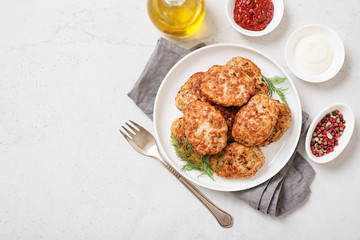 Juicy delicious meat cutlets in a white plate on a light gray table. Top view 