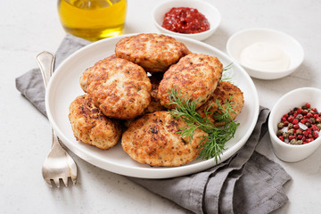 Juicy delicious meat cutlets in a white plate on a light gray table. 