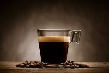 Keuken spatwand met foto Black coffee in glass cup with coffee beans on wooden table © winston