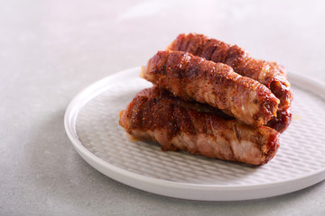 Bacon wrapped sausages on plate