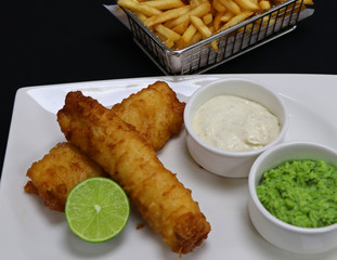 battered fried fish with tartar sauce, mushy peas and potato chips, known as fish and chips
