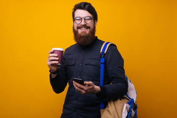 Handsome bearded  guy standing, holding drink and looking at camera. Tourism and communication concept.