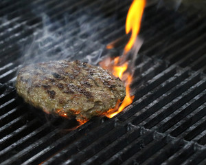 beef burger on barbecue with fire and smoke