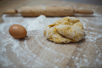 The girl prepares the dough for homemade noodles. On the table there is everything you need.