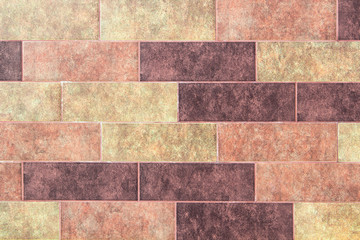 The texture of a brick wall of decorative multicolored rectangular bricks with noise, scratches and stains.